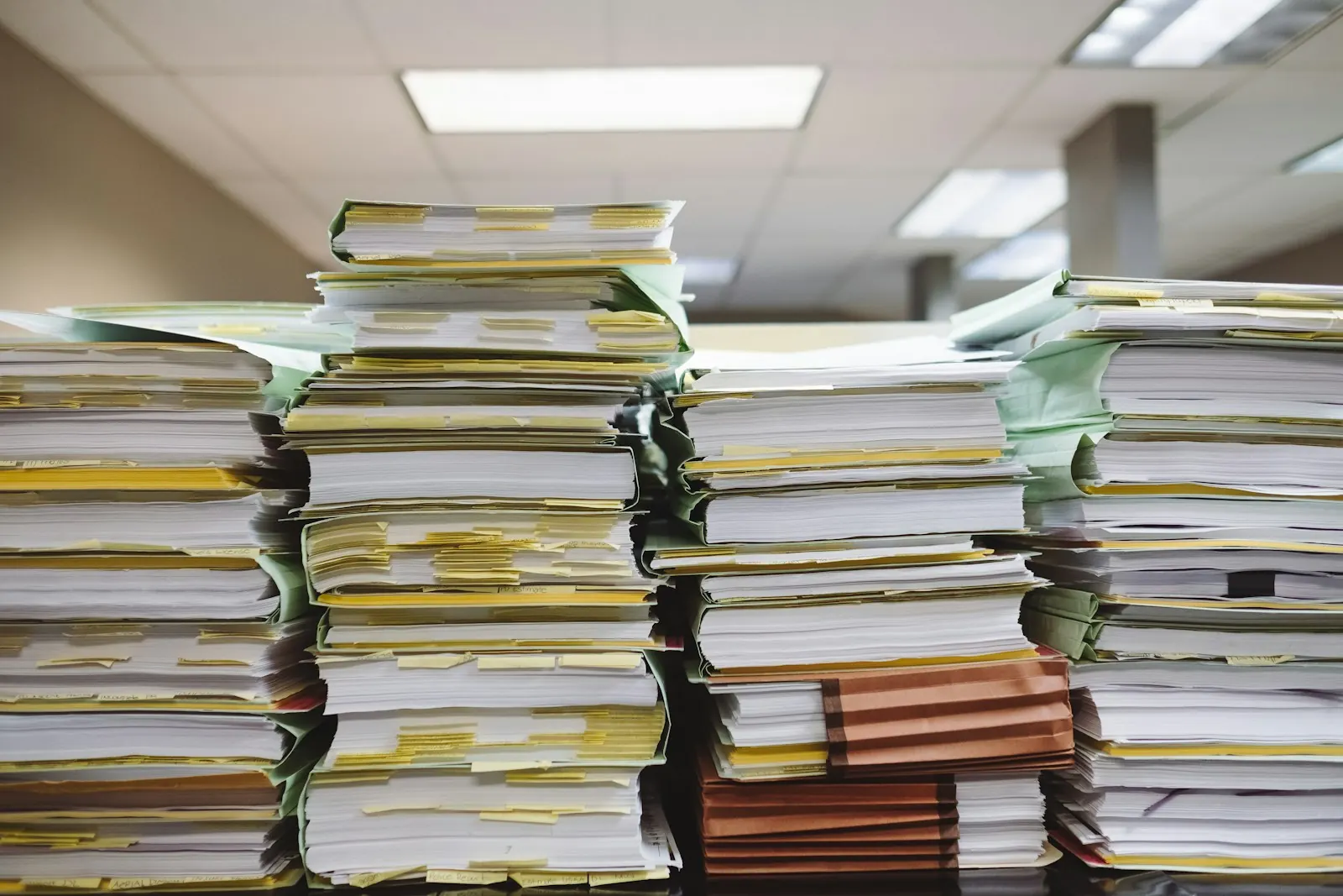 Tall stacks of paper files and folders in an office.